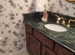 Dark-green-marble-vanity-top-with-cream-porcelain-tile-floor